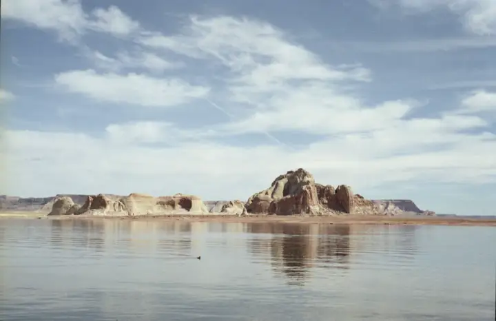Sandstone buttes across still water under a pale sky.